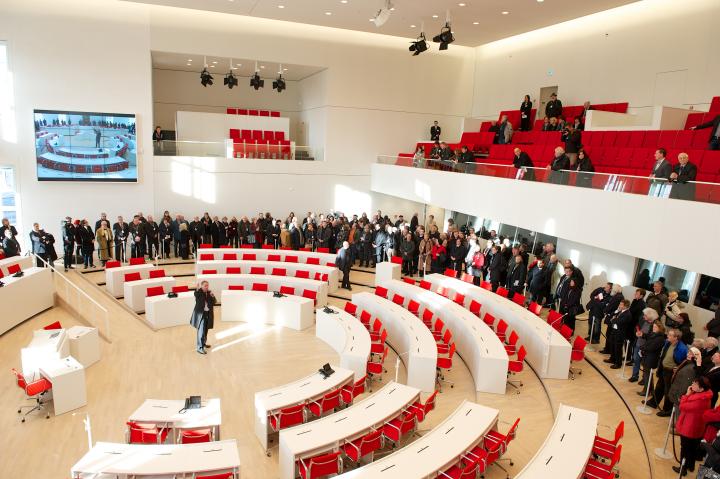 Landtagspräsident Gunter Fritsch erläutert den Besucherinnen und Besuchern des Eröffnungswochenendes die Sitzordnung im neuen Plenarsaal.