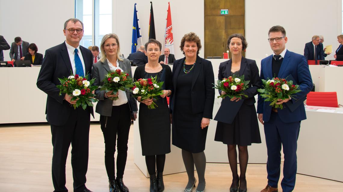 Landtagspräsidentin Britta Stark (3. v. r.) mit den gewählten Richter/innen Markus Möller, Christine Kirbach, Kathleen Heinrich-Reichow, Karen Sokoll und Dr. Michael Strauß (v. l. n. r.). Nicht im Bild: Dr. Julia Barbara Finck (Juli Zeh)