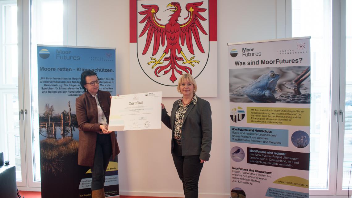 Landtagspräsidentin Prof. Dr. Ulrike Liedtke (r.) nahm das Zertifikat von der Geschäftsführerin der Flächenagentur Brandenburg Anne Schöps (l.) entgegen.