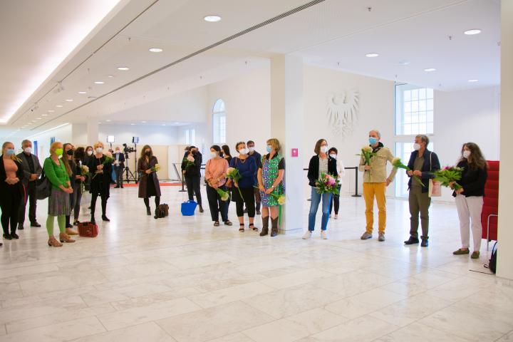 Überreichung von Blumen an die zwei Vertreterinnen des Brandenburgischen Verbands Bildender Künstlerinnen und Künstler e. V. Petra Schmidt Dreyblatt (1. v. r.) und Jutta Pelz (4. v. r.), sowie an einige der an der Ausstellung beteiligten Künstlerinnen und Künstler.