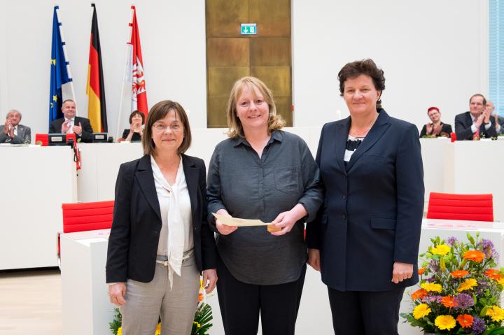 Anke Bienwald, Medaillenempfängerin auf Vorschlag der Fraktion Bündnis90/Die Grünen (m.) mit Laudatorin Ursula Nonnemacher, parlamentarische Geschäftsführerin (l.), und Landtagspräsidentin Britta Stark (r.)