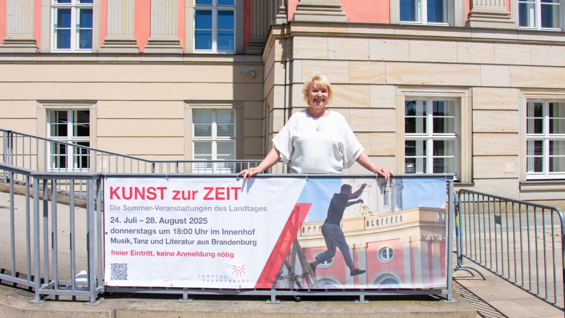 Landtagspräsidentin Prof. Dr. Ulrike Liedtke enthüllt das Banner der Sommer-Veranstaltungsreihe „Kunst zur Zeit 2025“ an der Kutschauffahrt des Landtages Brandenburg