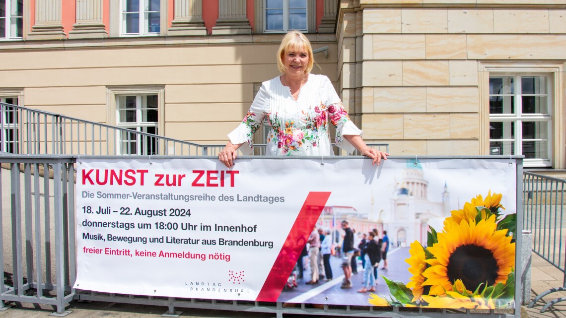 Landtagspräsidentin Prof. Dr. Ulrike Liedtke enthüllt das Banner der Sommer-Veranstaltungsreihe „Kunst zur Zeit 2024“ an der Kutschauffahrt des Landtages Brandenburg