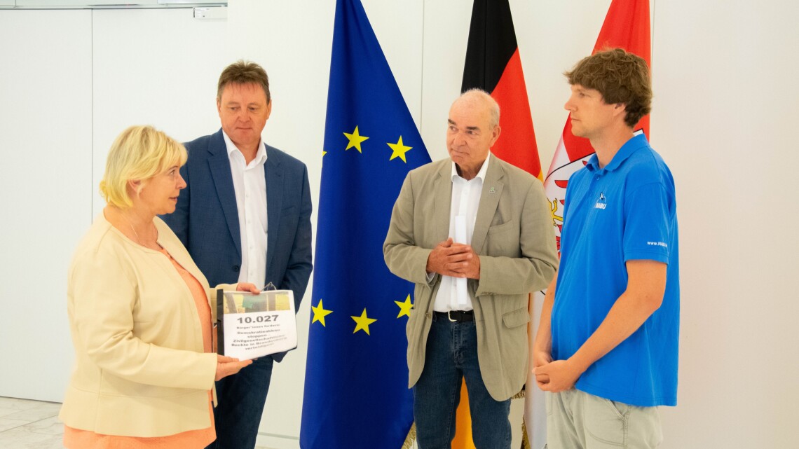 Landtagspräsidentin Prof. Dr. Ulrike Liedte (l.) nimmt, gemeinsam mit dem Vorsitzenden des Petitionsausschusses Udo Wernitz (2. v. l.), die Petition von Vertretern des BUND und des NABU entgegen.