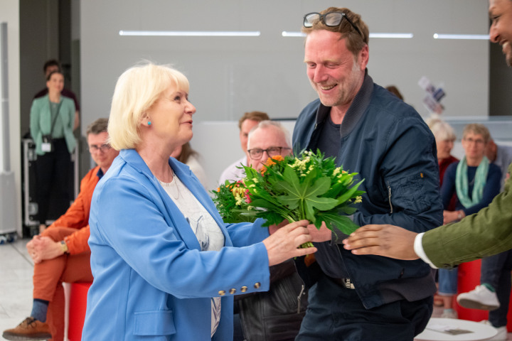 Landtagspräsidentin Prof. Dr. Ulrike Liedtke (l.) bedankt sich bei dem Herausgeber Jonathan Teklu (r.)