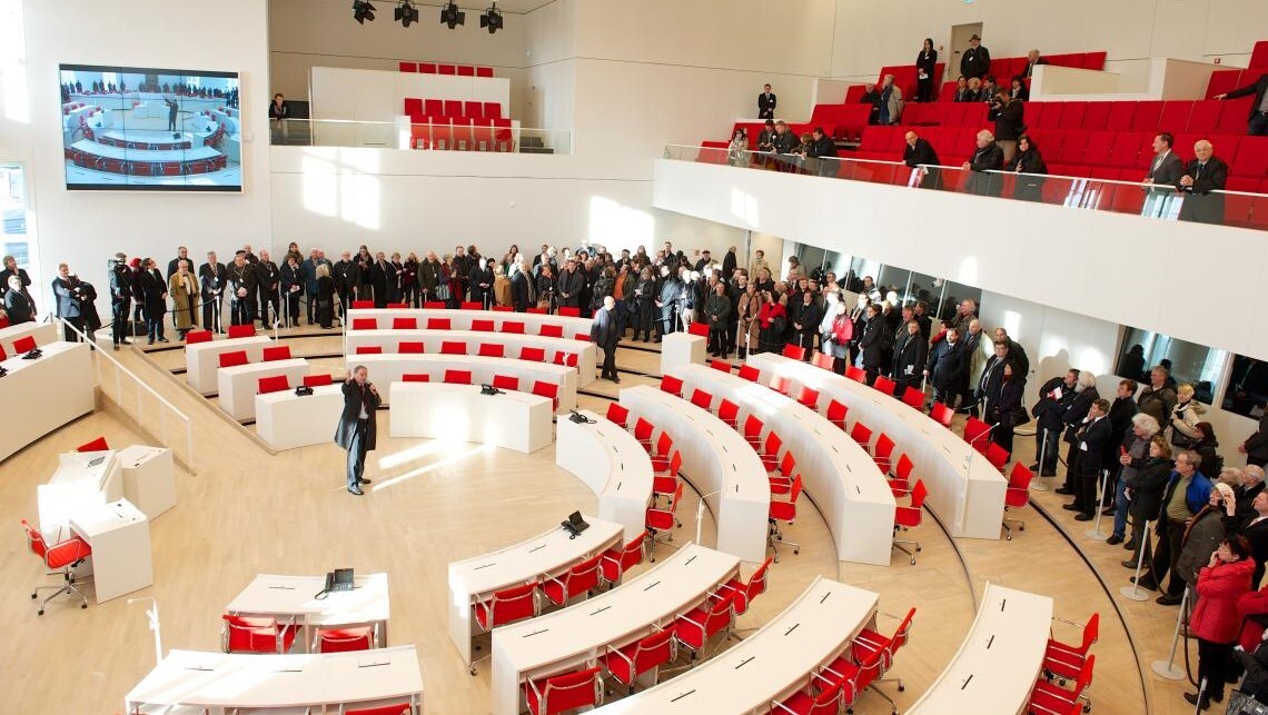 Eröffnungswochenende 18./19.01.2014: Der damalige Landtagspräsident Gunter Fritsch erläutert den Besucherinnen und Besuchern Sitzordnung im neuen Plenarsaal.
