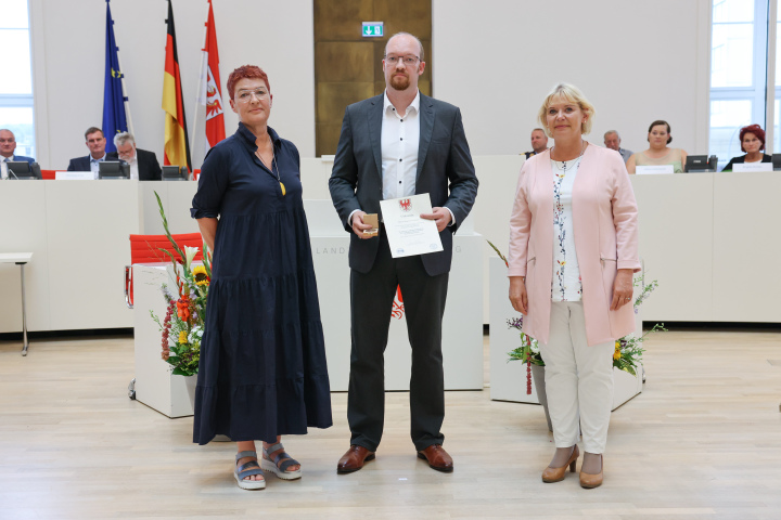 Übergabe der Medaille und Urkunde an den zu Ehrenden Marcus Grotian (m.)