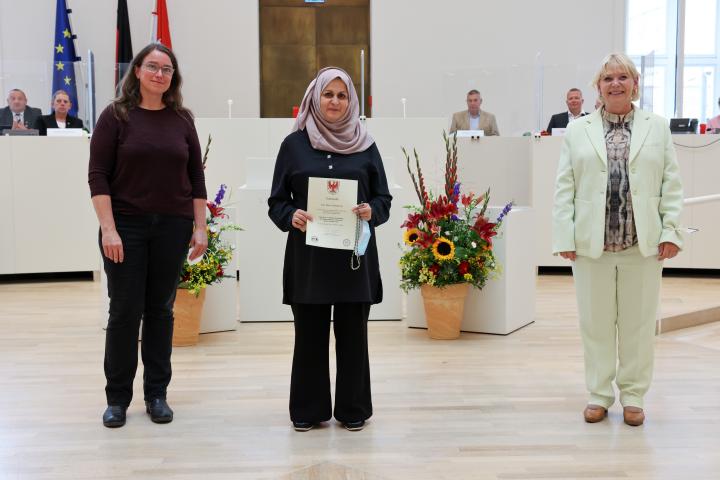 Übergabe der Medaille und Urkunde an die zu Ehrende Mona Abdelkarim (m.)