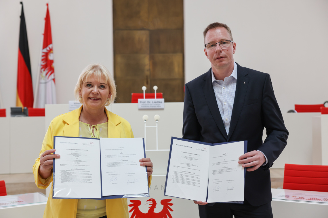 Landtagspräsidentin Prof. Dr. Liedtke (l.) und der Präsident des Abgeordnetenhauses von Berlin, Dennis Buchner (r.), mit der unterzeichneten Verwaltungsvereinbarung zur Zusammenarbeit in der Parlamentarischen Konferenz im Plenarsaal des Landtages Brandenburg